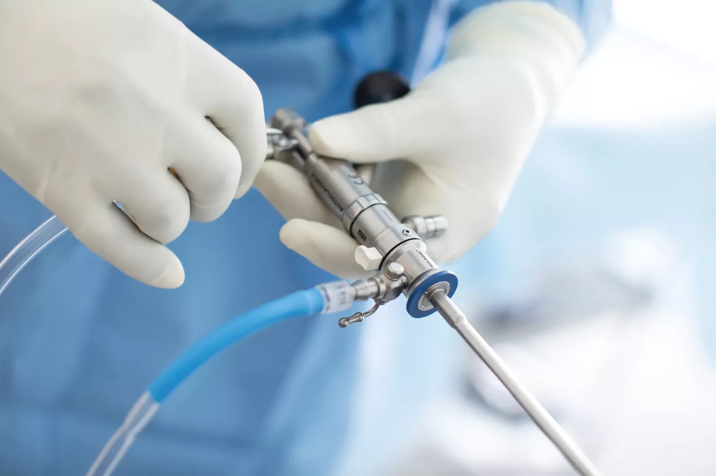 Handskeklædte hænder holder et medicinsk instrument