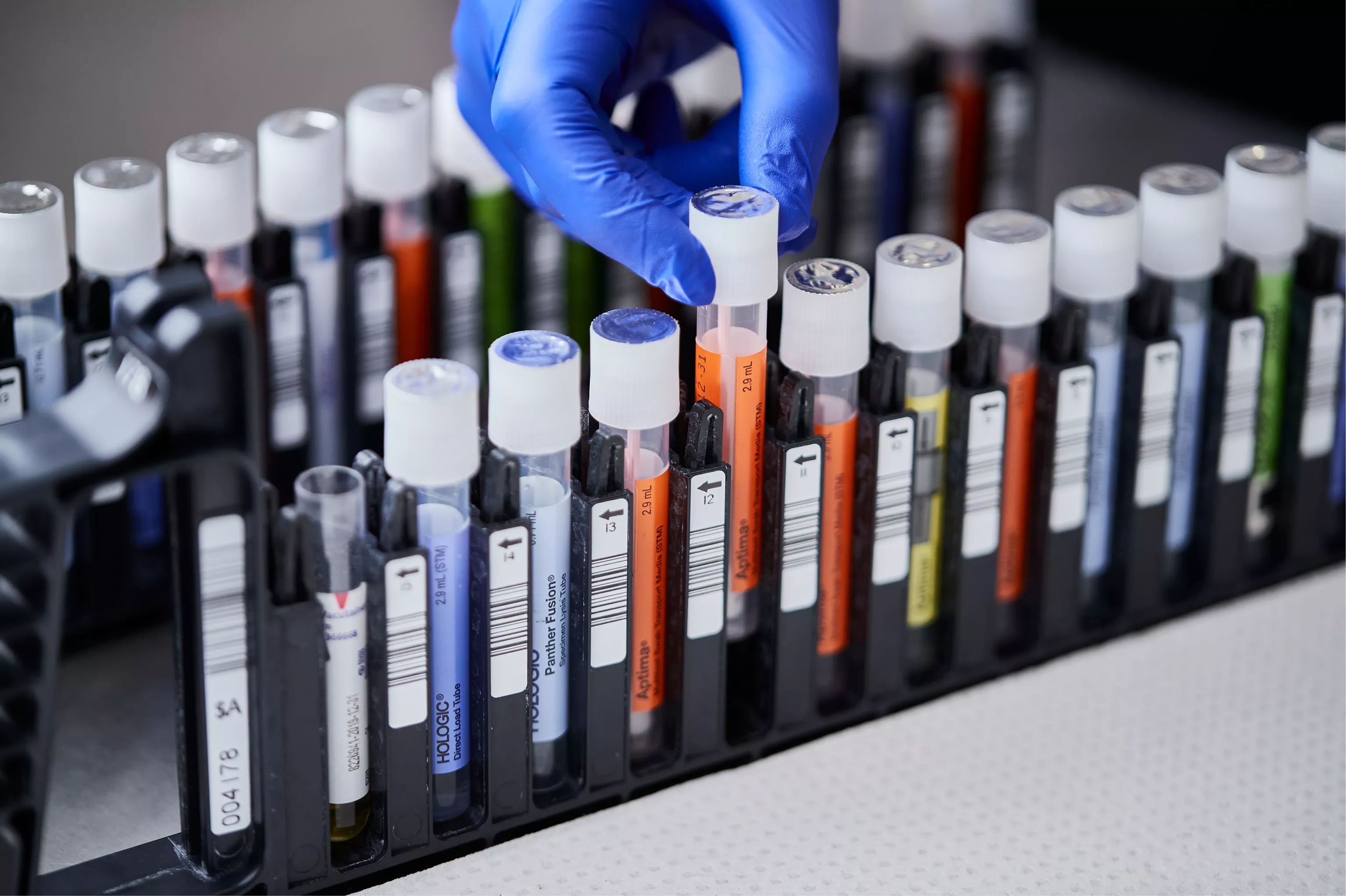 Hånd med handske tager hætteglas fra bakke