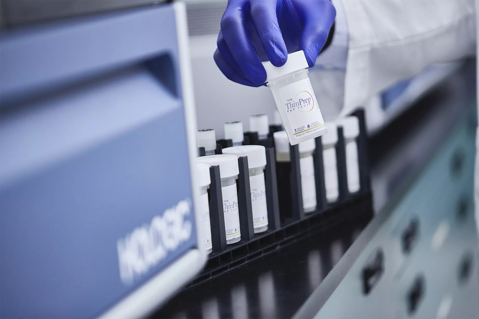 Hånd iført handske holder prøveglas